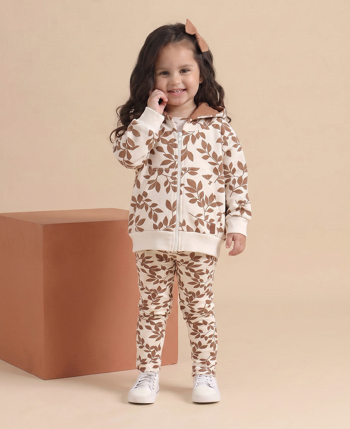 Detalhe da estampa Laurel folhagem de louro allover em tons terrosos sobre caramelo, no Conjunto Casaco Moletom + Legging da MiniMalista — 100% algodão premium, look pronto de outono e inverno pra menina
