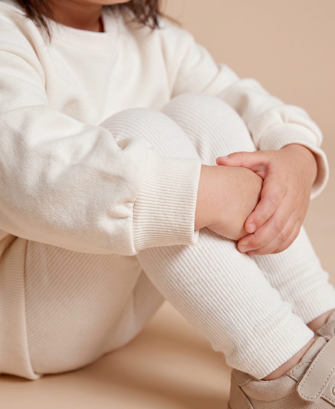 MiniMalista Conjunto Moletom + Calça Canelada em Branco Off vista costas. Moletom oversized soltinho + calça canelada slim, look infantil monocromático unissex, estética escandinava minimalista para bebê e criança.
