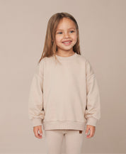 MiniMalista Conjunto Moletom + Calça Canelada Liso Bege Claro vista costas. Moletom oversized soltinho + calça canelada slim, look infantil monocromático unissex, estética escandinava minimalista para bebê e criança, cor neutra acolhedora.