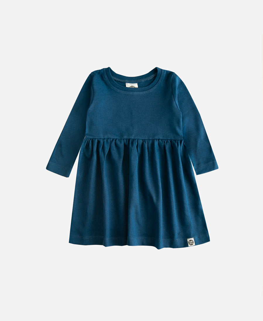 Menina vestindo Vestido Manga Longa Liso Azul Sky da MiniMalista Baby em Algodão Egípcio Safra Premium com proteção UV50+ permanente, look completo com laço jacaré coordenado, moda infantil inverno