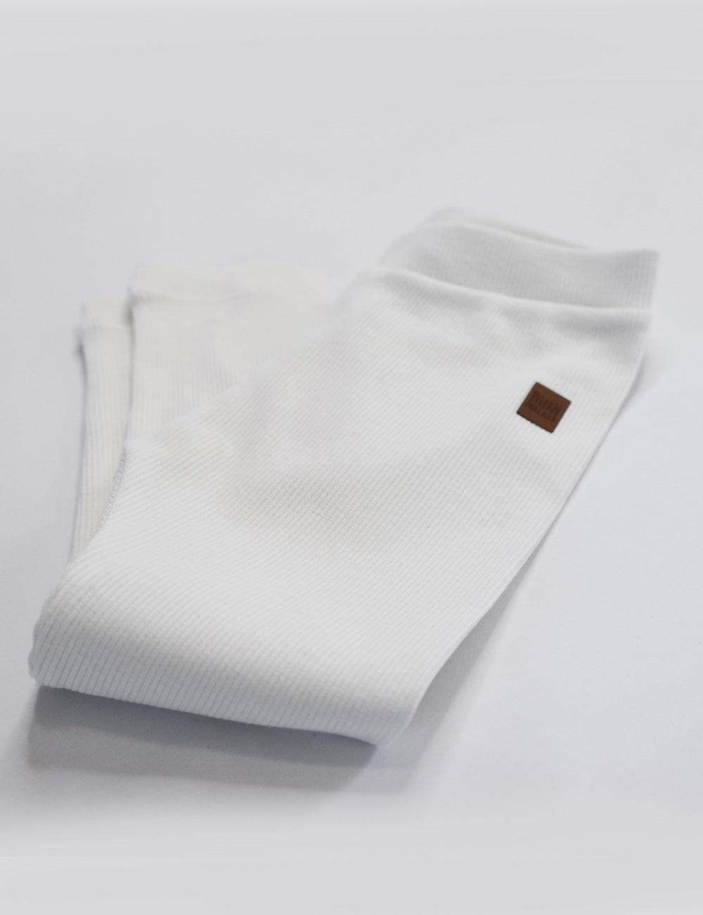 Calça Canelada Slim Liso Branco Off MiniMalista — calça infantil unissex 100% algodão em ribana, caimento slim ajustado, branco off atemporal que combina com qualquer estampa e cor, do bebê de 0-3 meses aos 5-6 anos.
